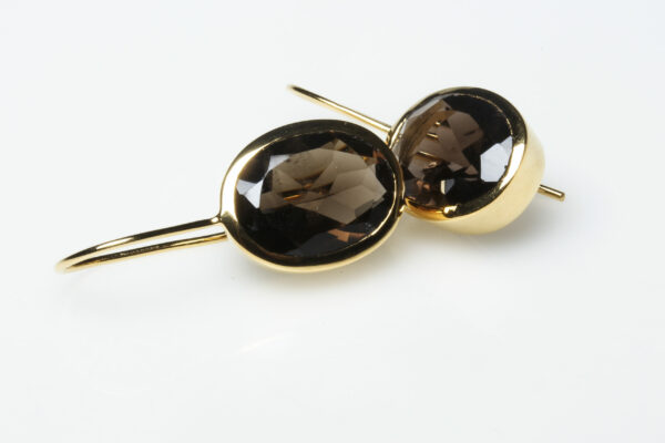 Picture of golden earrings with oval brown stones.