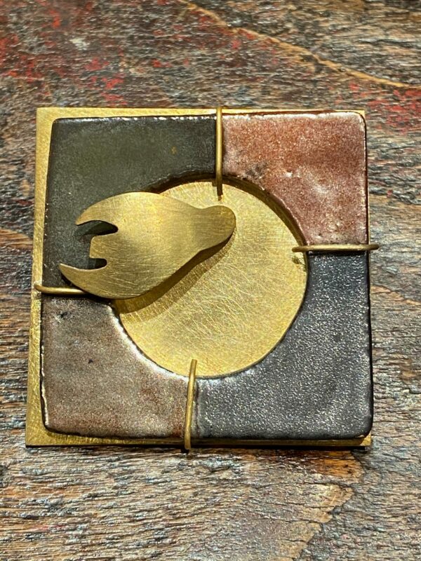 Enamelled stoneware and brass brooch.